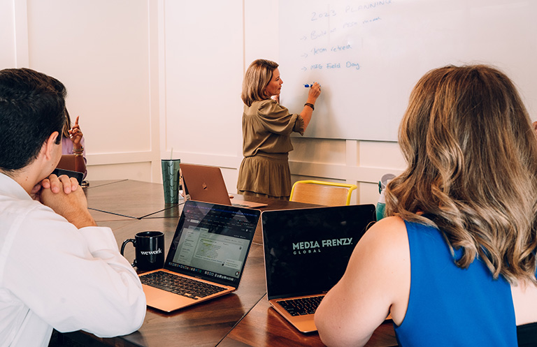 Sarah taking meeting notes on whiteboard